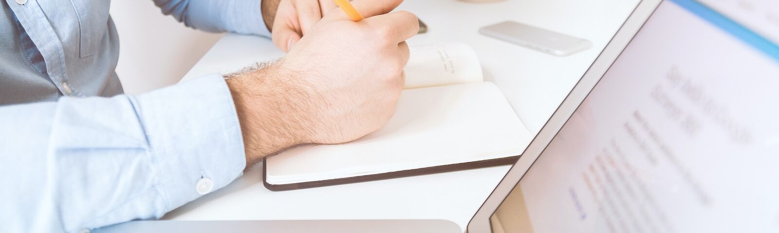 person writing on white notebook